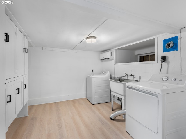 laundry area with a wall mounted AC, separate washer and dryer, sink, and light hardwood / wood-style flooring