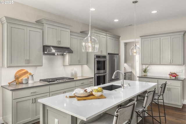 17641 NW Layla Dr, Portland, OR 97229 - kitchen featuring a sink, under cabinet range hood, appliances with stainless steel finishes, tasteful backsplash, and a breakfast bar area