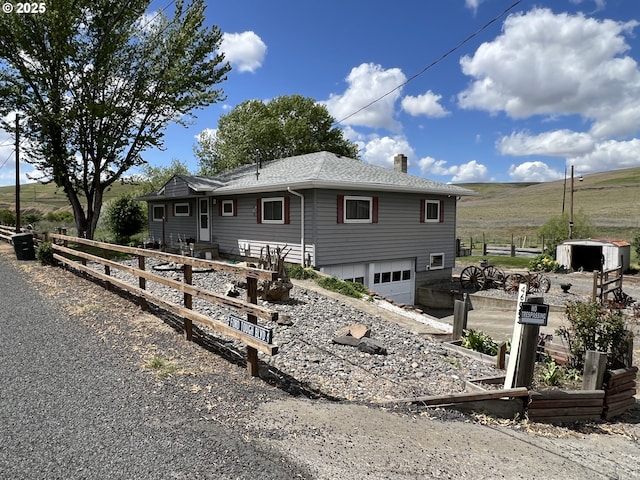 46083 Adams Rd, Pendleton, OR 97801 - back of house with a garage, gravel driveway, a chimney, roof with shingles, and a view of rural / pastoral area