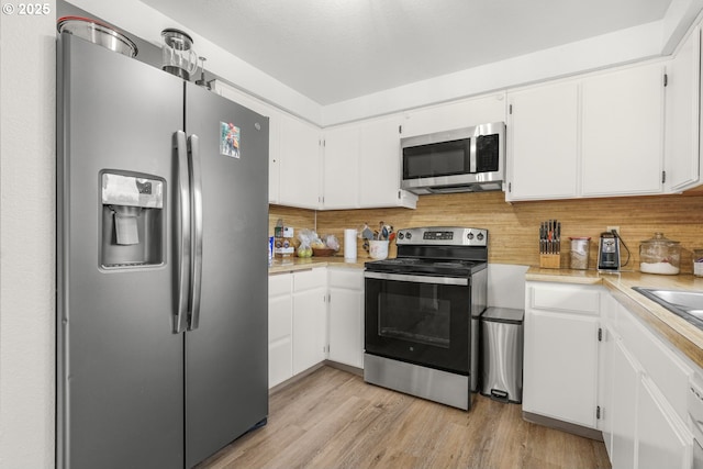 kitchen with light countertops, backsplash, white cabinets, and stainless steel appliances