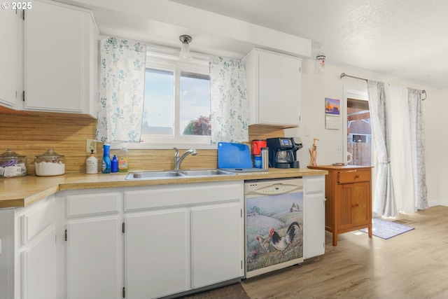 kitchen with a sink, light wood finished floors, white cabinets, and white dishwasher
