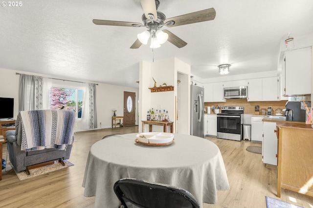 dining area with a ceiling fan and light wood-style flooring
