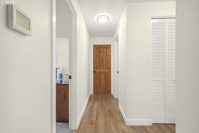 hall featuring baseboards and light wood-type flooring