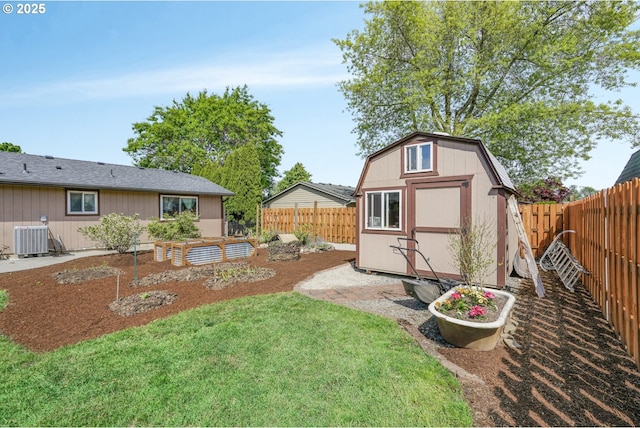 rear view of house with a garden, a storage shed, an outbuilding, central AC unit, and a fenced backyard