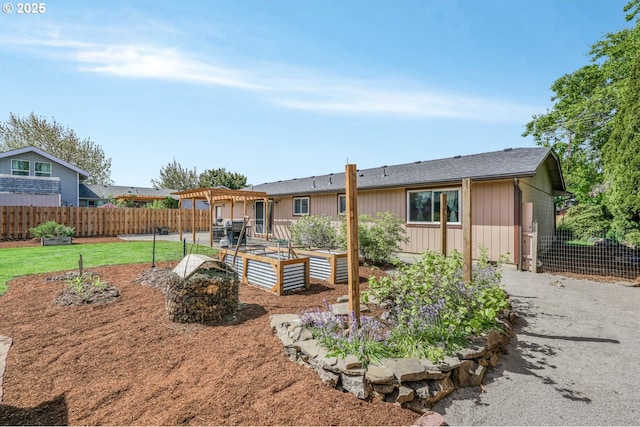 rear view of house with a garden, fence, a pergola, a patio, and a lawn