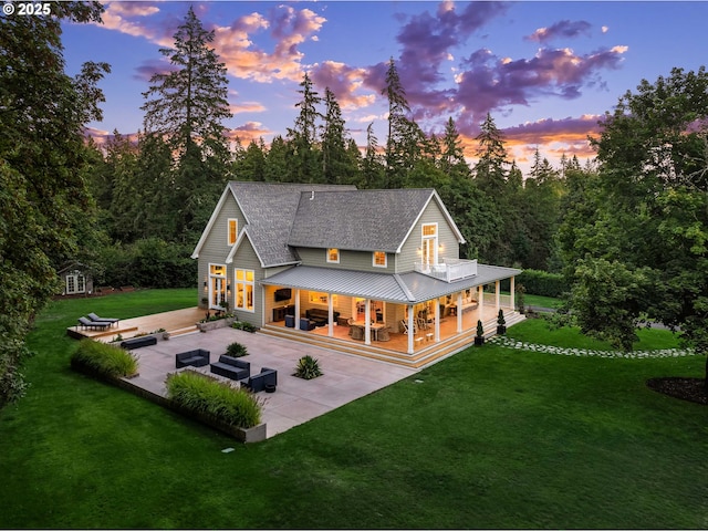 back house at dusk featuring a yard, a patio area, and outdoor lounge area