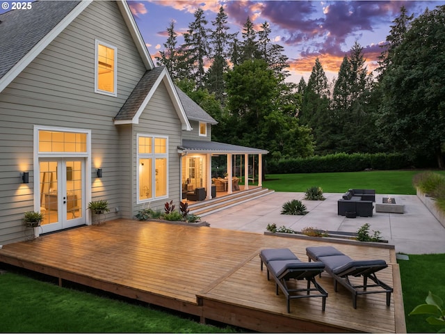 back house at dusk with a deck, a yard, outdoor lounge area, a patio area, and french doors