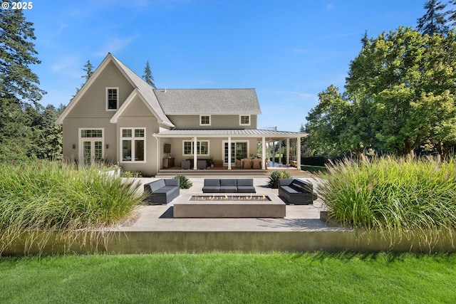 rear view of house with french doors, an outdoor living space with a fire pit, and a patio area