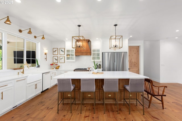 kitchen featuring stainless steel built in refrigerator, dishwasher, sink, and a kitchen island