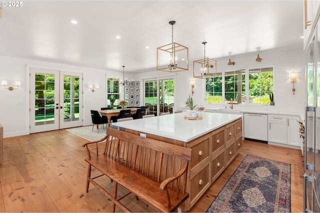 kitchen featuring decorative light fixtures, white cabinetry, dishwasher, a center island, and french doors