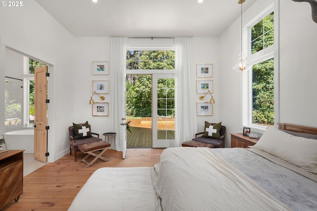 bedroom with multiple windows, access to exterior, and light hardwood / wood-style floors