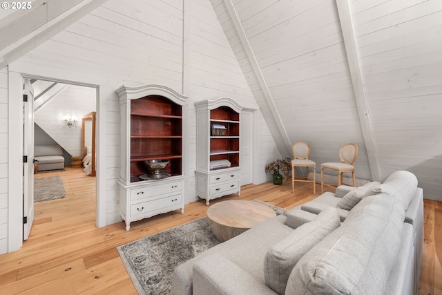 living room with wood walls, hardwood / wood-style floors, and vaulted ceiling with beams