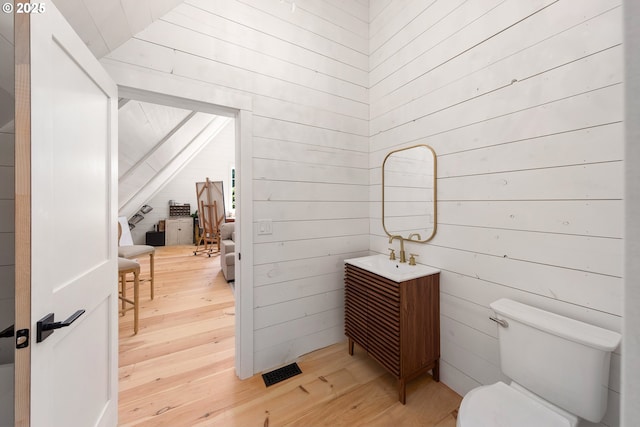 bathroom with vanity, hardwood / wood-style floors, toilet, and wood walls