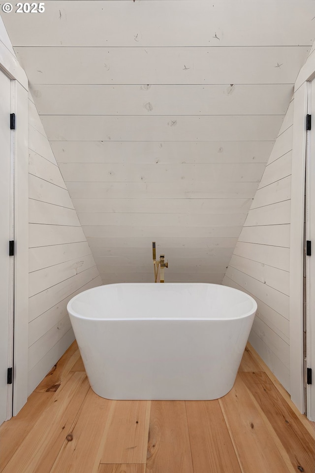 bathroom featuring hardwood / wood-style floors, a washtub, and wooden walls