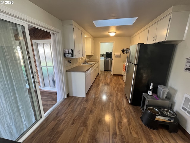 kitchen with a skylight, washing machine and clothes dryer, freestanding refrigerator, a sink, and dishwasher