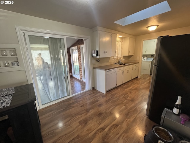 kitchen with white dishwasher, a skylight, a sink, freestanding refrigerator, and washer / dryer