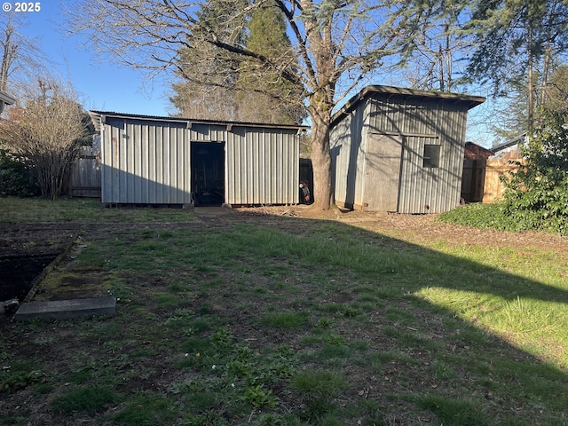 view of yard featuring a storage shed, an outbuilding, and fence