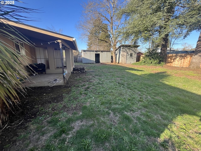 view of yard featuring an outbuilding, fence, a patio, and a shed