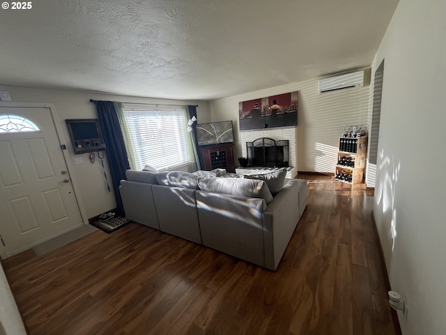 living area featuring a fireplace, dark wood finished floors, a textured ceiling, and a wall mounted air conditioner