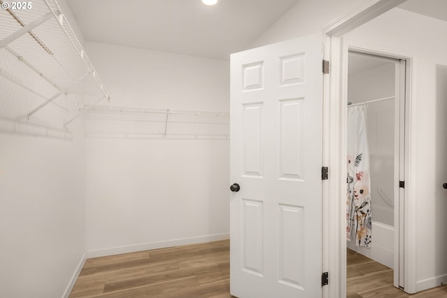 spacious closet with light wood-style flooring and lofted ceiling