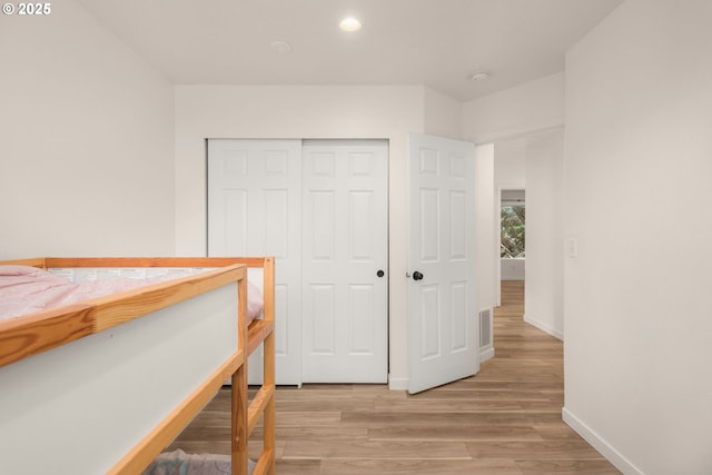 bedroom featuring light wood-style floors, recessed lighting, baseboards, visible vents, and a closet