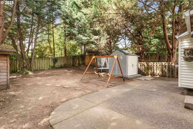 view of patio with a playground, an outbuilding, a fenced backyard, and a shed