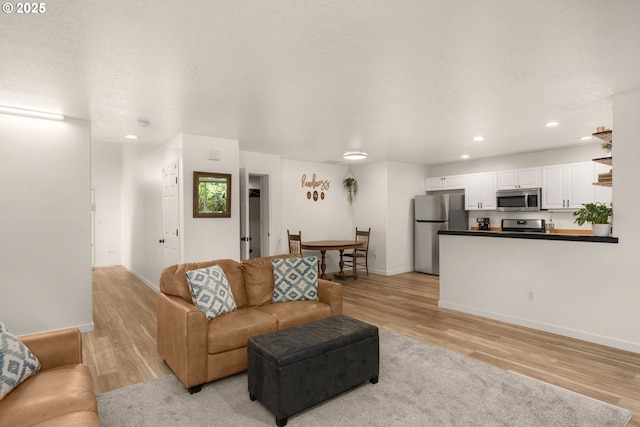 living area featuring recessed lighting, baseboards, and light wood finished floors
