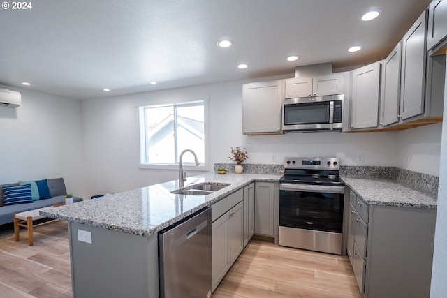 kitchen featuring appliances with stainless steel finishes, sink, light stone counters, light wood-type flooring, and gray cabinets