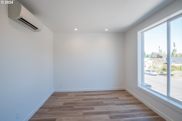 empty room with a wall mounted air conditioner and light hardwood / wood-style floors