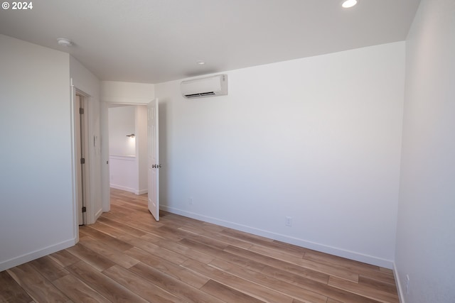 spare room with light wood-type flooring and an AC wall unit