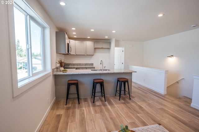 124 65th Pl, Springfield, OR 97478 - kitchen with a peninsula, recessed lighting, light wood finished floors, light stone counters, and a kitchen breakfast bar