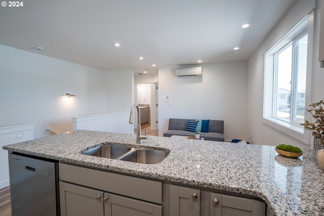 kitchen with a wall mounted air conditioner, light stone countertops, sink, gray cabinets, and stainless steel dishwasher