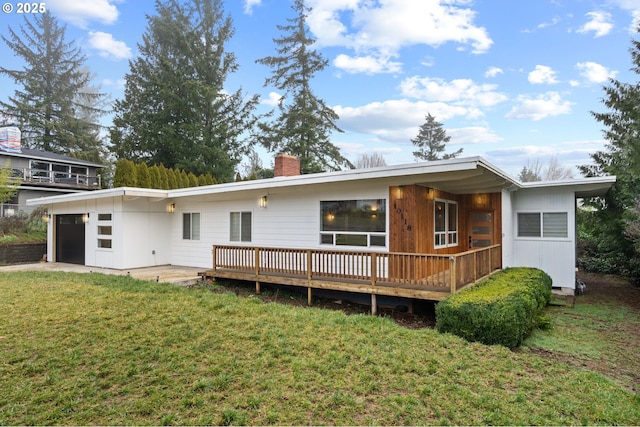 rear view of house featuring a yard, a garage, and a wooden deck