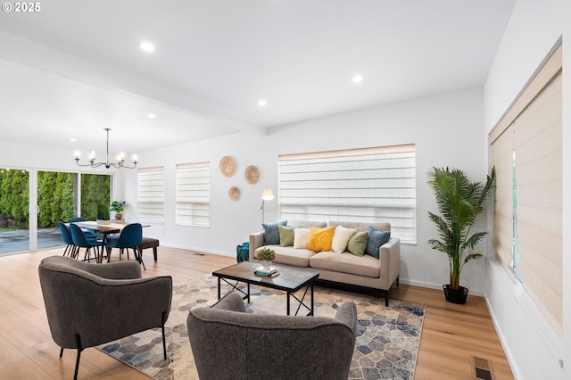 living room featuring beamed ceiling, light hardwood / wood-style floors, and a notable chandelier