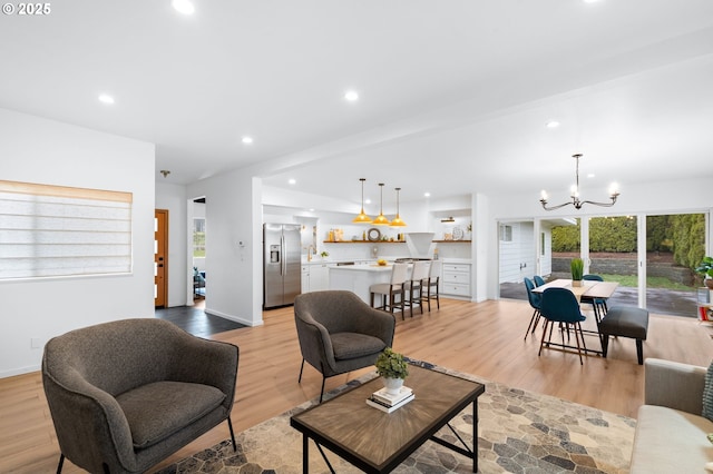 living room with a chandelier, beamed ceiling, and light hardwood / wood-style flooring