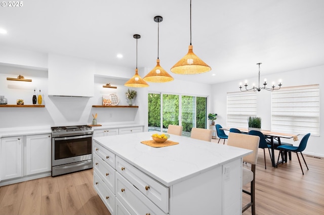 kitchen featuring white cabinets, pendant lighting, a kitchen island, and stainless steel gas range oven