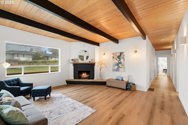 living room with wood ceiling, a brick fireplace, light hardwood / wood-style floors, and beamed ceiling