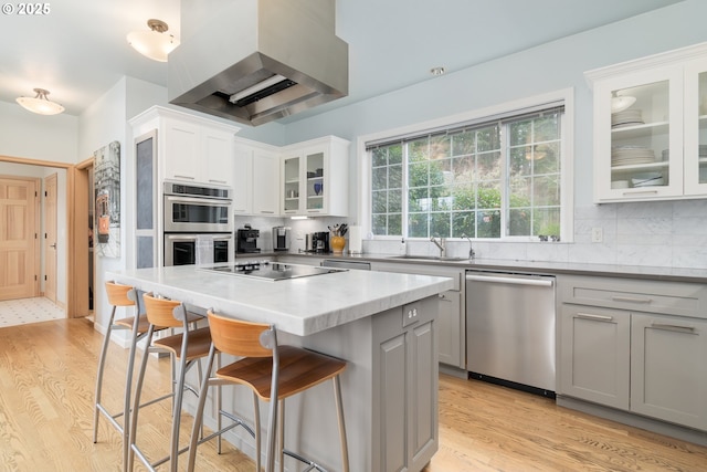 kitchen featuring appliances with stainless steel finishes, white cabinets, backsplash, a center island, and custom range hood