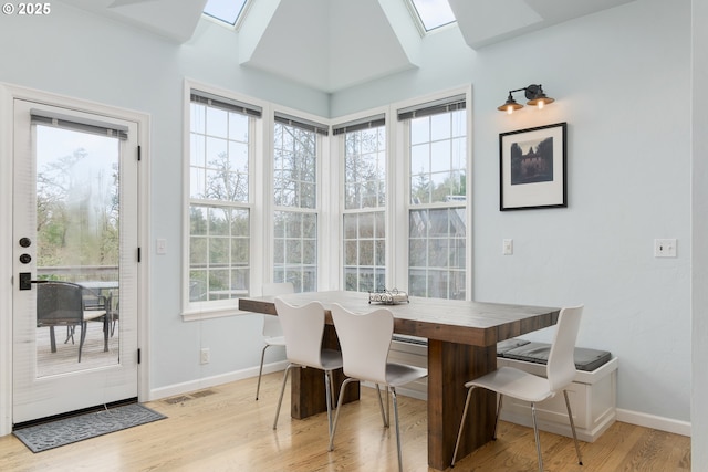 dining space with light hardwood / wood-style floors and a skylight