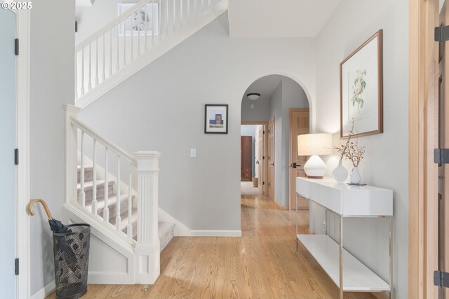 corridor featuring a towering ceiling and light hardwood / wood-style flooring