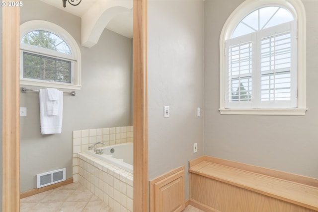 bathroom with a relaxing tiled tub and tile patterned floors