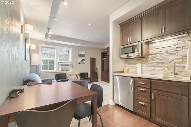 kitchen with appliances with stainless steel finishes, sink, backsplash, dark brown cabinetry, and light hardwood / wood-style floors