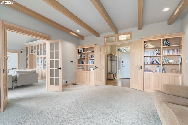 sitting room with carpet floors, beam ceiling, and french doors