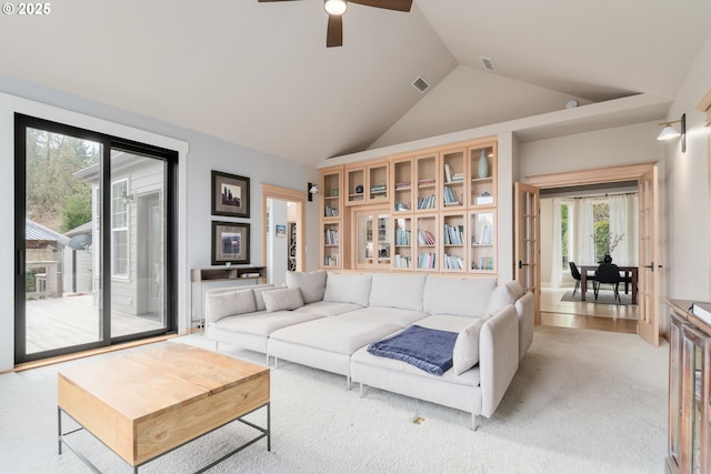 living room with ceiling fan, high vaulted ceiling, and light carpet