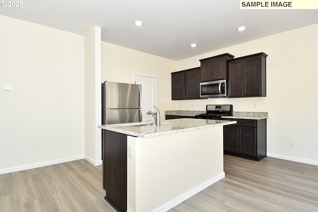 kitchen featuring sink, an island with sink, light wood-type flooring, and appliances with stainless steel finishes