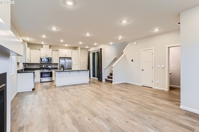 kitchen with light hardwood / wood-style floors, a center island, sink, white cabinetry, and appliances with stainless steel finishes