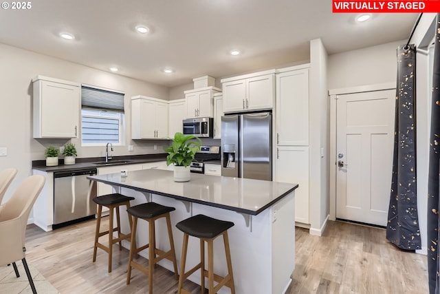 kitchen with light hardwood / wood-style floors, a center island, sink, white cabinetry, and stainless steel appliances