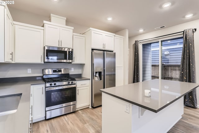 kitchen featuring light hardwood / wood-style floors, white cabinets, appliances with stainless steel finishes, and a center island