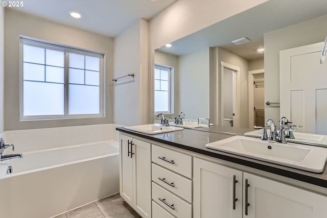 bathroom with a tub, vanity, and tile patterned flooring