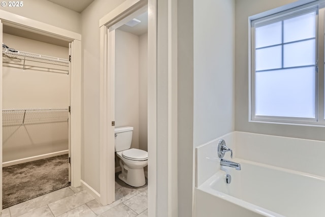 bathroom featuring a washtub, tile patterned floors, toilet, and plenty of natural light